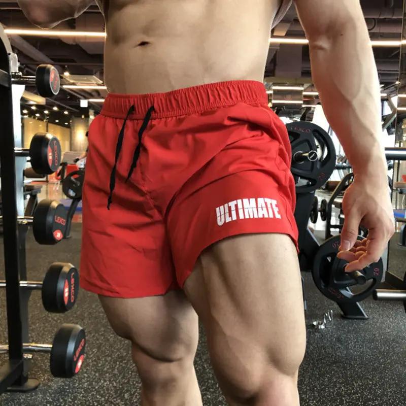 Men's red quick-dry three-quarter gym shorts with elastic waistband and black drawstrings, ULTIMATE logo on the leg